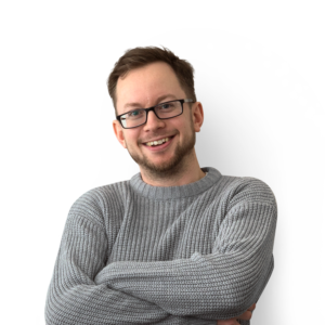 Man with folded arms wearing a grey jumper, short brown hair, beard and glasses.