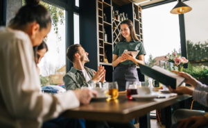 Group of people ordering food from the waitress. Waitress writing orders down on tablet.
