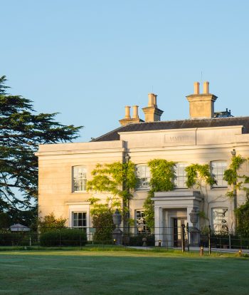 The Limewood Hotel exterior surrounded by large trees and blue skies